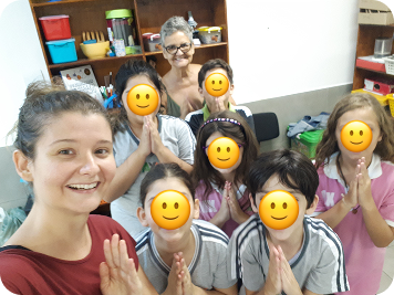 Débora e Ana, mãe e filha e instrutoras da Jornada Sai da Tela, com grupo de crianças em uma aula de yoga, em clima de alegria e acolhimento