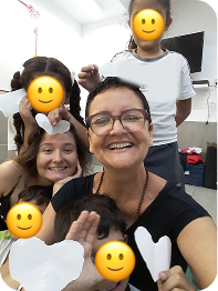 Professora de yoga com crianças sorridentes, finalizando prática com gesto de gratidão